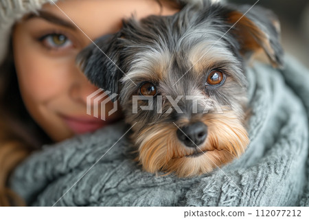 A woman hugs a schnauzer dog, keeping him warm 112077212