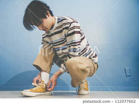 藍色背景中穿黃色鞋子的年輕人 藍色背景中穿黃色鞋子的年輕人 112077602