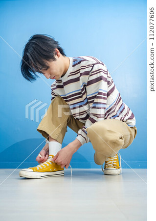 Young man wearing yellow shoes on blue background 112077606