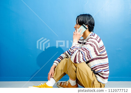 Young man making a phone call on blue background 112077712