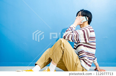 Young man making a phone call on blue background 112077713