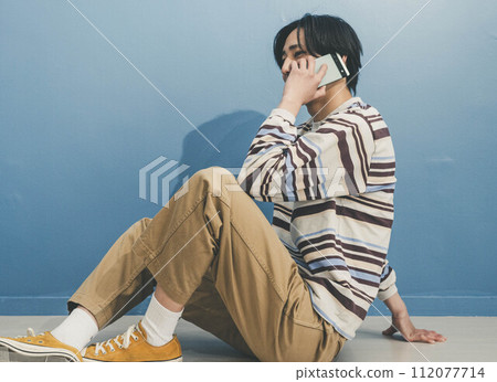 藍色背景打電話的年輕人 112077714