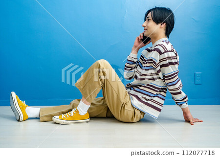 藍色背景打電話的年輕人 112077718