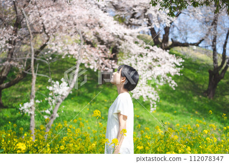 Woman standing relax and calm in yellow flower blossom field leisure in nature on spring season 112078347