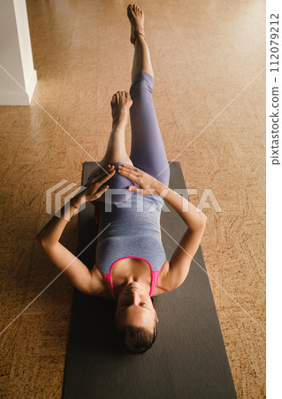 Slender girl doing yoga with a big massage roller on the floor 112079212