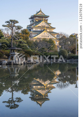 Osaka Castle tower reflected in the Japanese garden pond early in the morning 112079519
