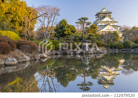 Osaka Castle tower reflected in the Japanese garden pond early in the morning 112079520