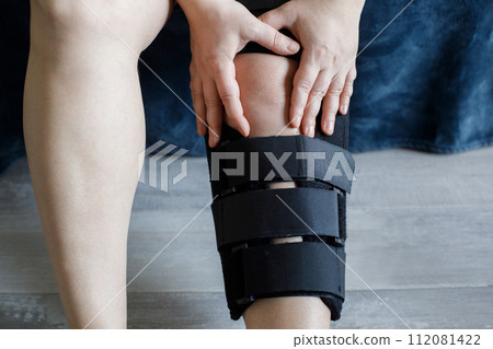 Photo of women leg with knee brace sitting at home 112081422