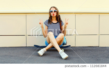Portrait of cheerful young woman with skateboard in the city Portrait of cheerful young woman with skateboard in the city 112081844