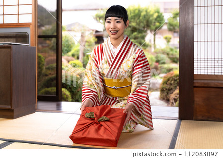 A woman in Japanese clothes offering a gift 112083097
