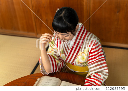 A woman in Japanese clothes reading a book A woman in Japanese clothes reading a book 112083595