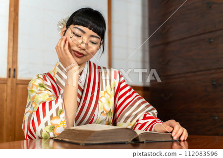 A woman in Japanese clothes reading a book 112083596
