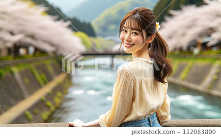A woman enjoying cherry blossoms by the riverside 112083800