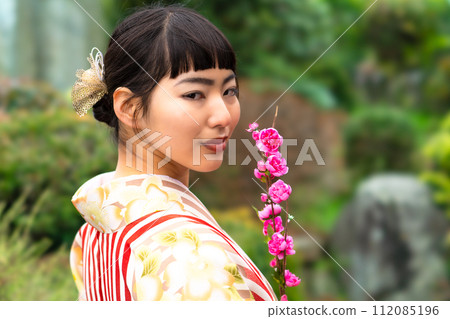 一個穿著日式服裝的女人站在花園裡 112085196