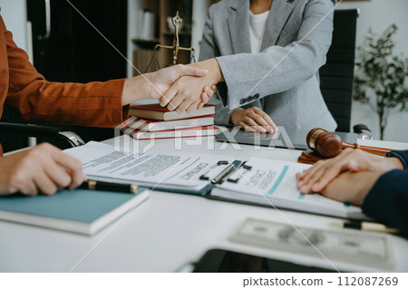 Lawyer shaking hands with client after discussing final contract agreement. 112087269