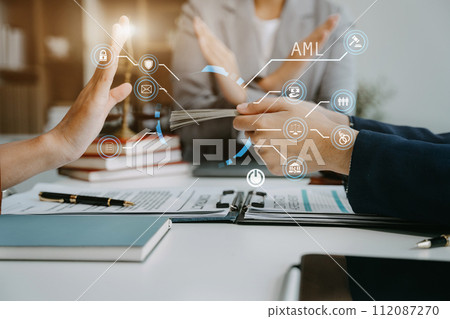 Judge in a courtroom using laptop and tablet with AML anti money laundering icon on virtual screen. Judge in a courtroom using laptop and tablet with AML anti money laundering icon on virtual screen. 112087270