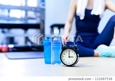 在私人健身房訓練的年輕女子時鐘和時間背景材料肌肉訓練女孩冷色 112087538