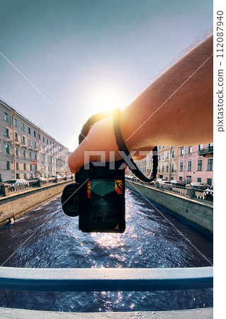 male hand holding a camera against the a river between old buildings to take a picture, pov, point of view perspective male hand holding a camera against the a river between old buildings to take a picture, pov, point of view perspective 112087940