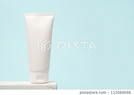 White cosmetic tube staying on the stone podium, blue background with copy space White cosmetic tube staying on the stone podium, blue background with copy space 112088098