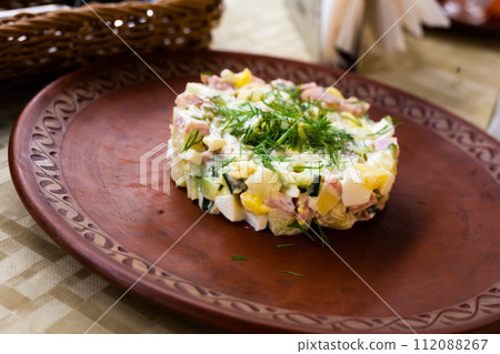 Salad with peas and mayonnaise, served in a cylinder on a clay plate 112088267