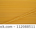 A single diagonal line of uncooked spaghetti noodles crosses a yellow background, adding a dynamic angle to the composition. 112088511