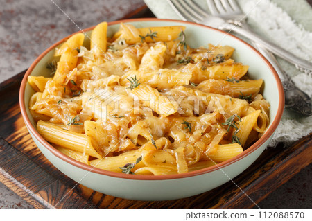 Delicious French onion pasta penne with caramelized onions, fragrant thyme, garlic and gruyere cheese close-up on a bowl. Horizontal 112088570