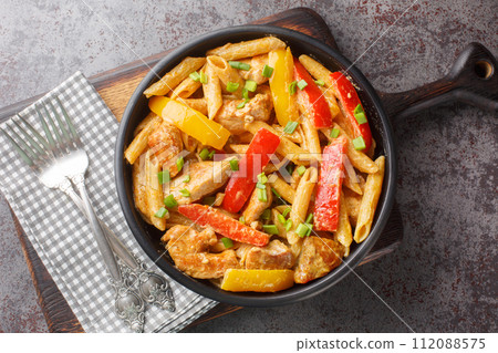 Rasta Pasta is a Penne cooked in rich creamy sauce with Jerk Chicken, sauteed onions, Sweet Peppers, garlic closeup on the bowl. Horizontal top view Rasta Pasta is a Penne cooked in rich creamy sauce with Jerk Chicken, sauteed onions, Sweet Peppers, garlic closeup on the bowl. Horizontal top view 112088575