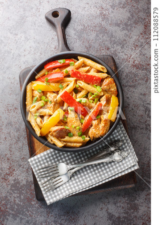 Creamy Jerk Chicken Jamaican Rasta Pasta closeup on the bowl. Vertical top view Creamy Jerk Chicken Jamaican Rasta Pasta closeup on the bowl. Vertical top view 112088579