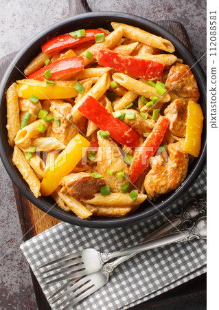 Rasta pasta is a very colorful dish consisting of grilled chicken, a combination of different bell peppers, a thick coconut sauce and Caribbean spices close-up. Vertical top view Rasta pasta is a very colorful dish consisting of grilled chicken, a combination of different bell peppers, a thick coconut sauce and Caribbean spices close-up. Vertical top view 112088581