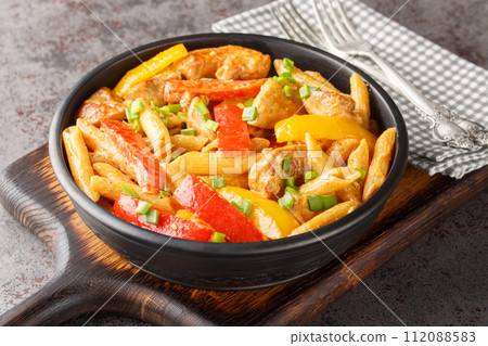 Rasta Pasta is a Penne cooked in rich creamy sauce with Jerk Chicken, sauteed onions, Sweet Peppers, garlic closeup on the bowl. Horizontal Rasta Pasta is a Penne cooked in rich creamy sauce with Jerk Chicken, sauteed onions, Sweet Peppers, garlic closeup on the bowl. Horizontal 112088583
