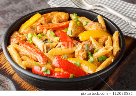 Jamaican Rasta Pasta tossed in Jamaican jerk seasoning, chicken, coconut milk and with colourful sauteed bell peppers closeup on the bowl. Horizontal Jamaican Rasta Pasta tossed in Jamaican jerk seasoning, chicken, coconut milk and with colourful sauteed bell peppers closeup on the bowl. Horizontal 112088585
