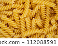 Highly detailed close-up of uncooked fusilli pasta showcasing the texture and shape of this classic Italian ingredient. 112088591