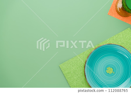 Green place setting for St Patricks dinner with a clover. Monochrome plate glass and glitter placemats. St Patrick's holiday background for greeting cards or banner templates 112088765