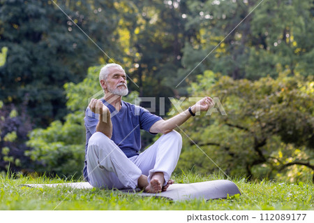 Elderly gentleman meditating in a peaceful outdoor environment, exemplifying health and tranquility. 112089177