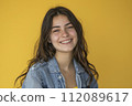 happy teen girl. Dressed in a cowboy jacket. Yellow background 112089617