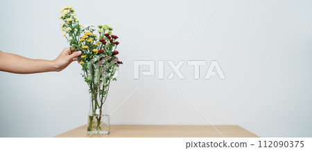 Woman hand arrange Colorful flowers bouquet in mason jar on table background. Happy day with fresh flower 112090375