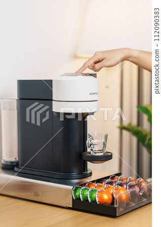 hand making Espresso Coffee by Coffee Maker Machine with Capsule of roasted coffee bean on wood table bar. Daily beverage drink at Home, Apartment and Office concept hand making Espresso Coffee by Coffee Maker Machine with Capsule of roasted coffee bean on wood table bar. Daily beverage drink at Home, Apartment and Office concept 112090383