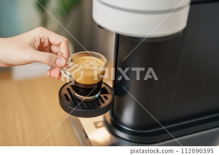 Espresso cup with steam and froth during Coffee making Coffee by Coffee Maker Machine on wood table bar. Cafe shop, Daily beverage drink at Home, Apartment and Office concept 112090395