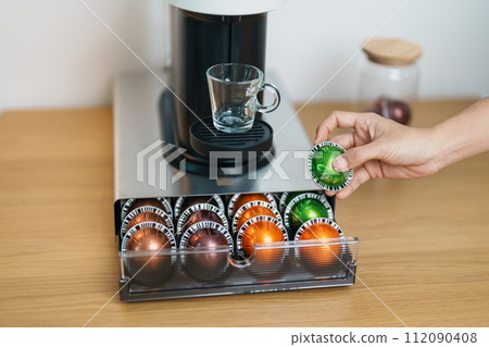hand making Espresso Coffee by Coffee Maker Machine with Capsule of roasted coffee bean on wood table bar. Daily beverage drink at Home, Apartment and Office concept 112090408