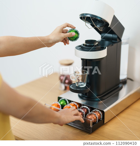 hand making Espresso Coffee by Coffee Maker Machine with Capsule of roasted coffee bean on wood table bar. Daily beverage drink at Home, Apartment and Office concept 112090410