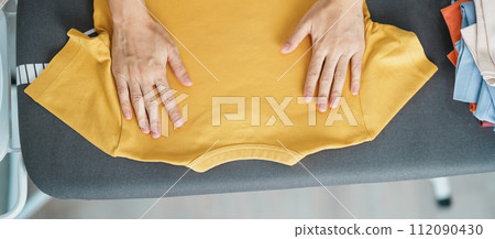 Woman hold Electric hot iron press T shirt clothes on ironing board, Intelligent automatic steam iron. Laundry, Housework, Housekeeping, Domestic hygiene, household of chores and daily routine concept Woman hold Electric hot iron press T shirt clothes on ironing board, Intelligent automatic steam iron. Laundry, Housework, Housekeeping, Domestic hygiene, household of chores and daily routine concept 112090430