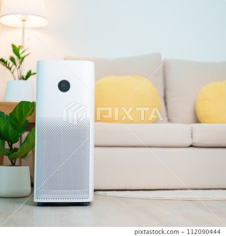 Air Purifier in cozy living room. Purification system for filter and cleaning or removing dust PM2.5 HEPA and virus in home. Allergy, Pure air, health lifestyle, Wellness life and Air Pollution 112090444