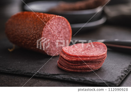 Smoked salami sausages on black table. 112090928