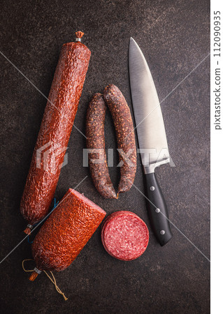 Smoked salami sausages on black table. Top view. Smoked salami sausages on black table. Top view. 112090935