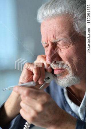 Portrait of sad sick senior man calling doctor 112091851