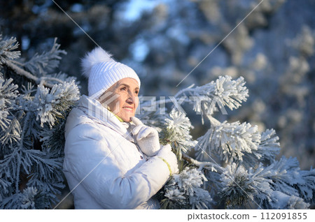 Happy old woman posing in the winter park Happy old woman posing in the winter park 112091855