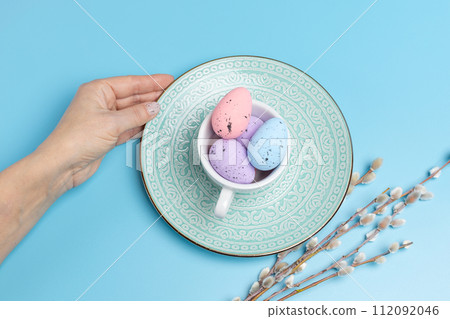 Cup with colored Easter eggs on the blue background. Cup with colored Easter eggs on the blue background. 112092046