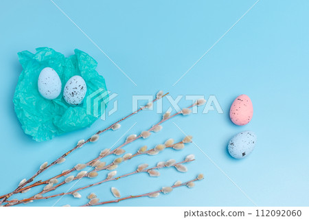 Nest with colored Easter eggs on the blue background. 112092060
