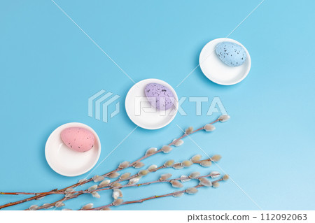 Saucers with colored Easter eggs on the blue background. Saucers with colored Easter eggs on the blue background. 112092063
