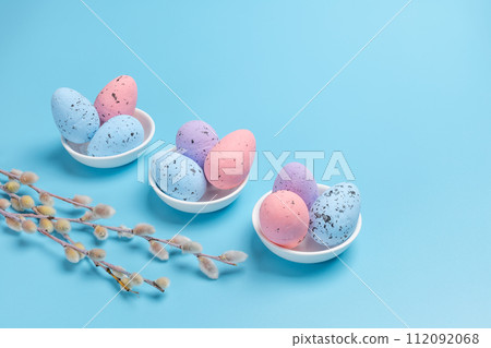 Saucers with colored Easter eggs on the blue background. 112092068